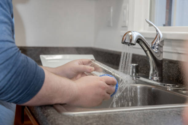 istock Man washes dishes in steaming hot water at kitchen sink 1288033551