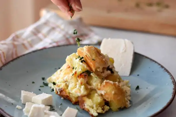 Freshly cooked potatoes gnocchi whit cheese and herbs/ Pouring herbs over the dish/ Closeup still life food photography
