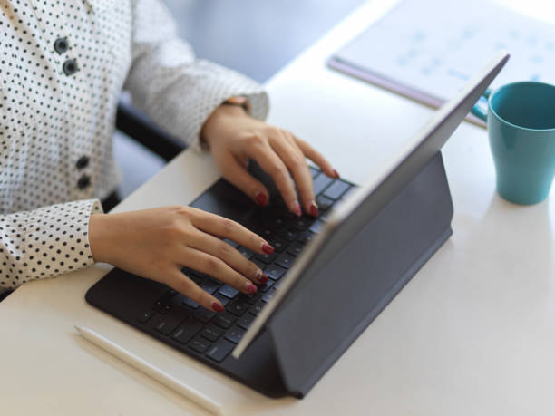 istock Top view of female hands typing on tablet keyboard on white worktable 1288039300