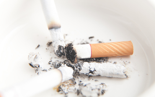 White ashtray with a cigarette. Smoking