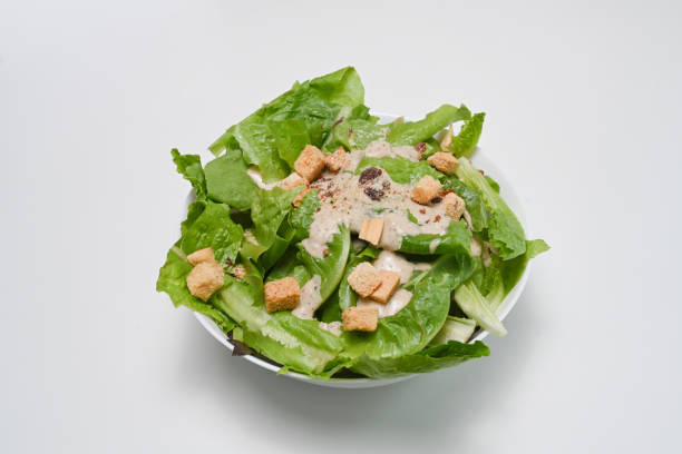 istock Fresh caesar salad in a bowl isolated on white background. 1288048107