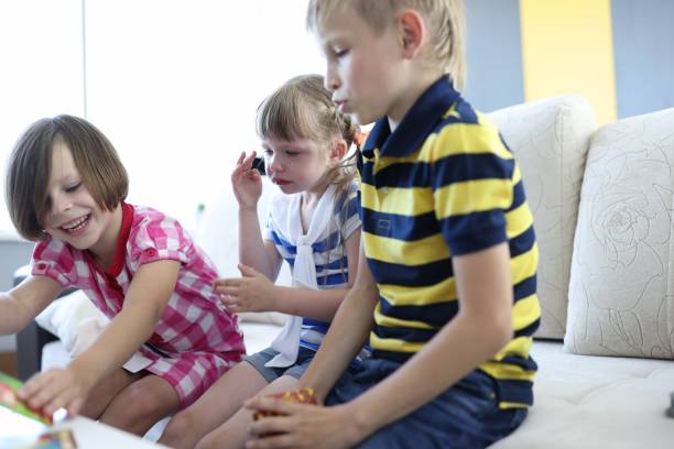 istock Three children play board game one girl sits and cries. 1288048122