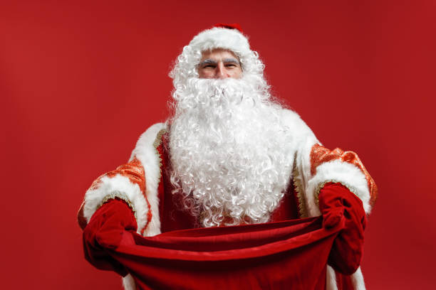 istock Santa Claus in red mittens hands a gift bag to the camera 1288049364