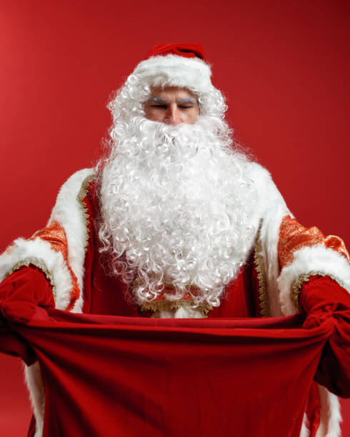istock Santa Claus in red mittens hands a gift bag to the camera 1288049368