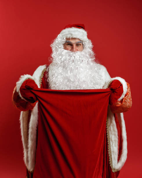 istock Santa Claus in red mittens hands a gift bag to the camera 1288049401