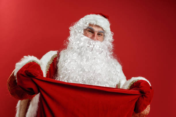 istock Santa Claus in red mittens hands a gift bag to the camera 1288049420