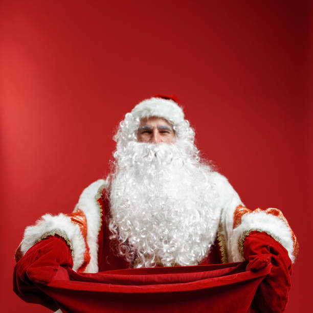 istock Santa Claus in red mittens hands a gift bag to the camera 1288049478