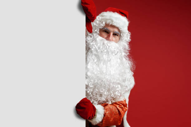 istock Santa Claus looks out from behind a white empty wall 1288049486