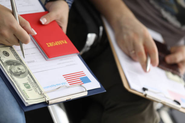 istock Man and woman are holding folder with application for visa and dollars at consulate 1288051827