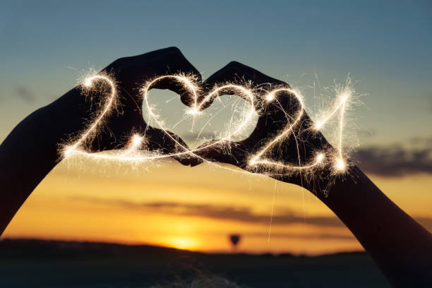 silhueta de coração ao pôr do sol com brilho 2021 - sparkler sparks new years eve human hand - fotografias e filmes do acervo