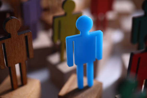 istock Blue plastic man stand against brown wooden crowd. 1288057933