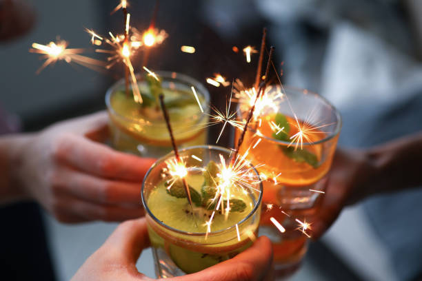 istock Three hands hold three glasses with cocktail and sparklers close-up. 1288057935