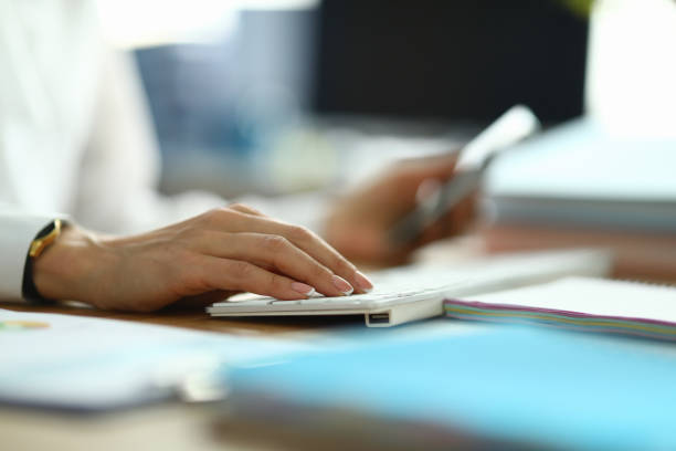 Woman in white coat hold her hand on white keyboard and type text.