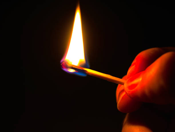 istock burning match in a hand against a black background 1288065920