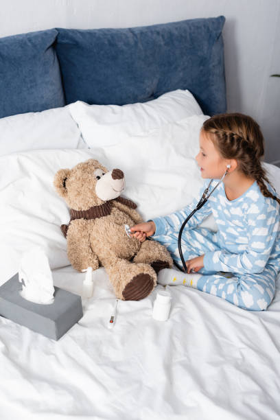 istock girl examining teddy bear with stethoscope while playing in bed 1288067786