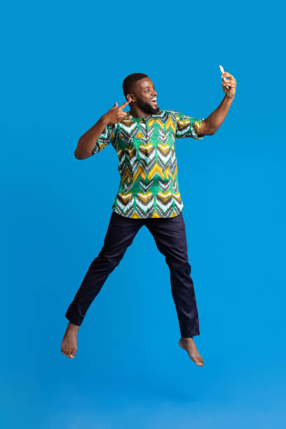 Happy black guy in african costume taking selfie