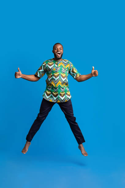 istock Happy black guy jumping up over blue background 1288069011