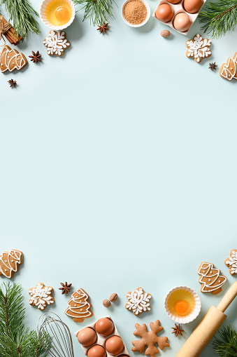 Christmas vertical cooking banner with traditional cookies with ingredients on light blue background. Space for text. View from above.