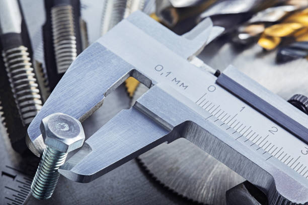 istock Measuring with vernier caliper bolt diameter for locksmithing work on steel plate. Locksmithing workshop. 1288071131