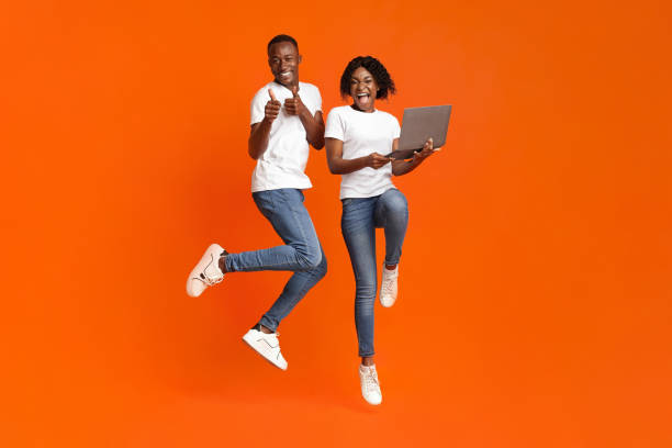 istock Excited black couple jumping up with laptop 1288073786