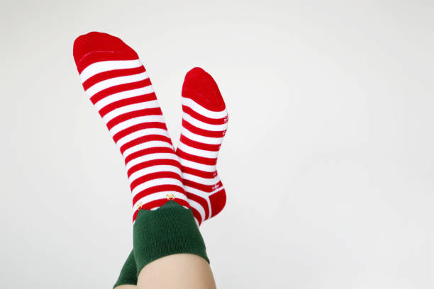 istock Female feet in Christmas socks on white background 1288075178