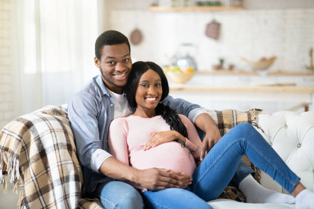istock Beautiful pregnant couple hugging on sofa at home 1288075213