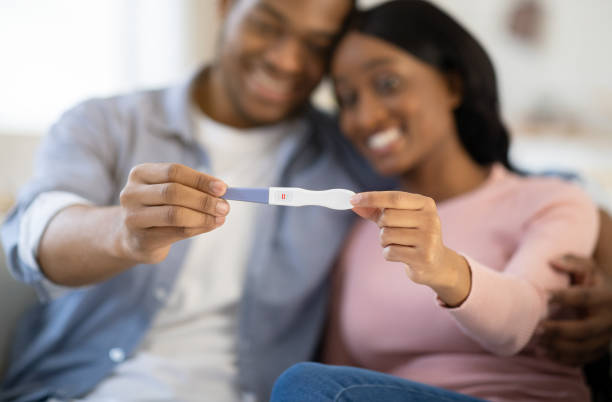 istock Young balck couple showing positive pregnancy test at home, selective focus on hands 1288075260