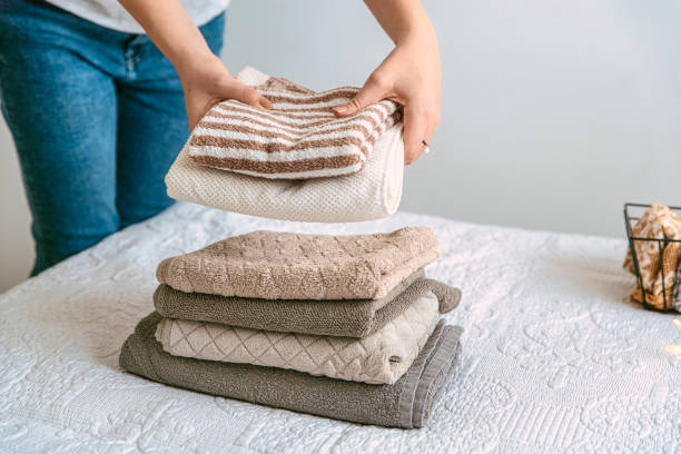 istock Woman folding stack of fresh laundry and towels, organizing laundry in boxes and baskets. 1288079779