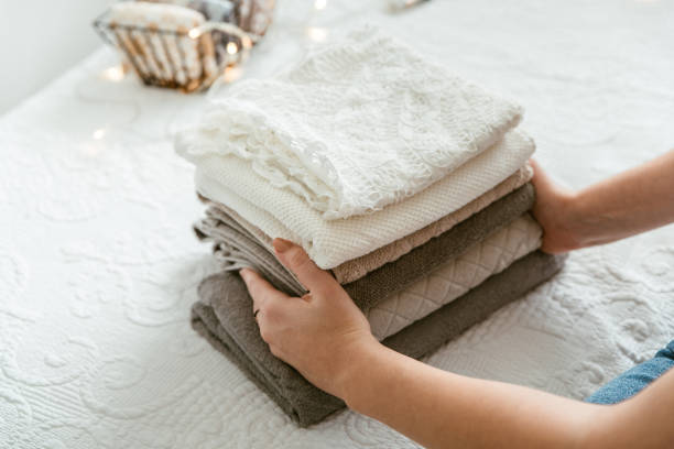 istock Woman folding stack of fresh laundry and towels, organizing laundry in boxes and baskets. 1288079816