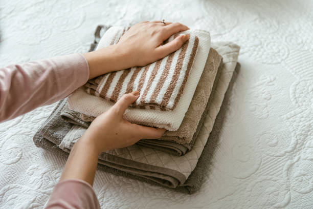 Woman folding clothes in bedroom, organizing laundry in boxes and baskets.