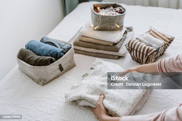 Woman Folding Stack Of Fresh Laundry Organizing Clothes And Towels In Boxes And Baskets Stock Photo - Download Image Now
