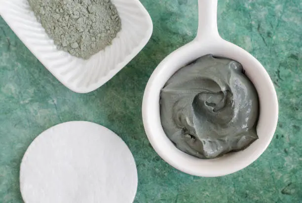 Photo of Gray (green) bentonite clay in the bowl. Clay texture close up. Diy mask and body wrap recipe. Natural beauty treatment and spa. Top view, copy space