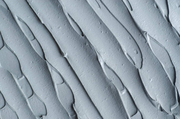 istock Gray bentonite facial clay (mask, face cream, body wrap) texture close up, selective focus. Abstract background with brush strokes. 1288083054