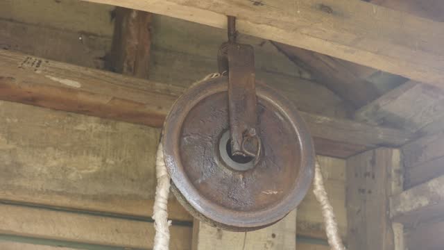 Old pulley in wooden water well house 4K video