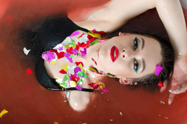girl with bright makeup in a bath with red water.