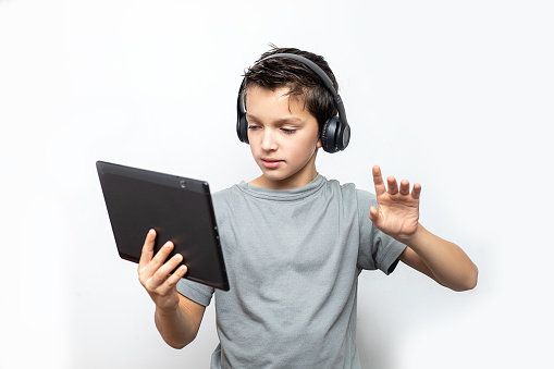 Photo of Teenage caucasian boy using tablet with headphones. Technology e-learning concept. Isolated white background. Digital communication.
