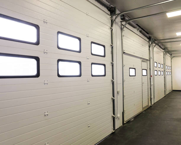 Row of overhead sectional doors in a multi-seat car garage. Inside view. stock photo