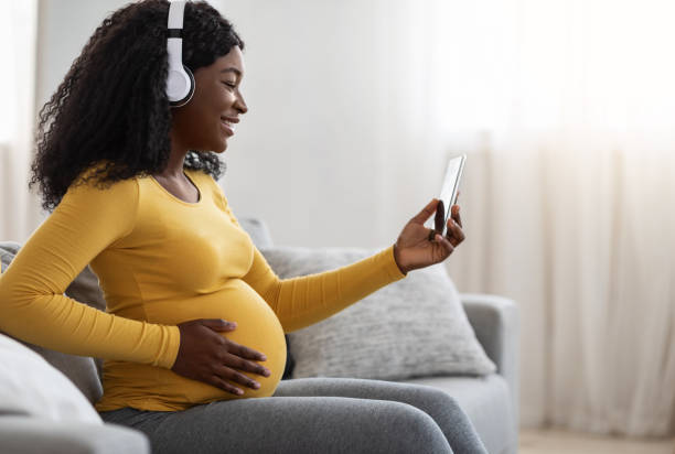istock Pregnant black lady enjoying music, using mobile app 1288089615