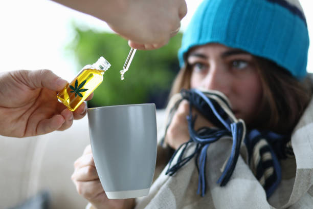 Yung woman sick with flu is dripping into cup with drops of marijuana extract closeup Yung woman sick with flu is dripping into cup with drops of marijuana extract closeup. Legal use of drugs based on marijuana concept. cannabinoid stock pictures, royalty-free photos & images