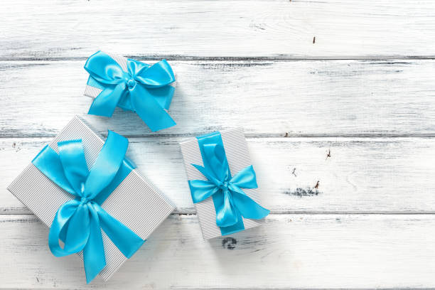 istock Gift boxes with blue ribbon on a white old wooden background. Top view, flat lay 1288090130
