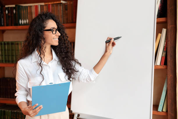 istock Smiling woman in glasses posing near blank flipchart 1288092675