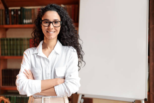 mulher confiante em óculos posando perto de quadro branco em branco - presenter young adult women marketing - fotografias e filmes do acervo