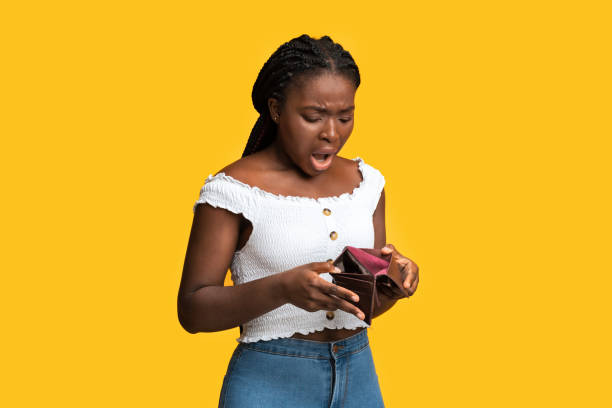 Poverty and absence of money. Shocked african american woman checking empty wallet Poverty and absence of money. Shocked african american woman checking empty wallet, frustrated black lady searching for cash, standing isolated over yellow studio background, copy space begging currency beggar poverty stock pictures, royalty-free photos & images