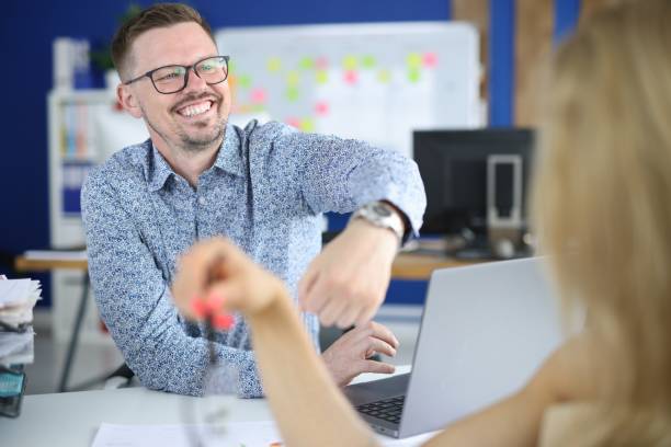 istock Cheerful man in glasses show client watch on his hand at workplace. 1288094045
