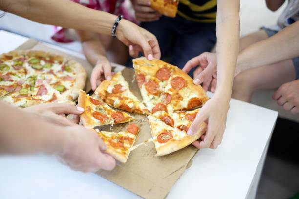 istock Delicious pizza close-up cut into pieces on white table. 1288094139