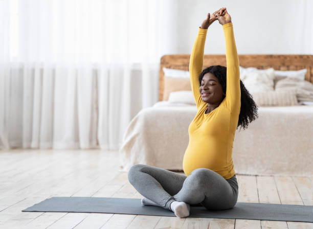 istock Happy black pregnant lady stretching at home 1288094593