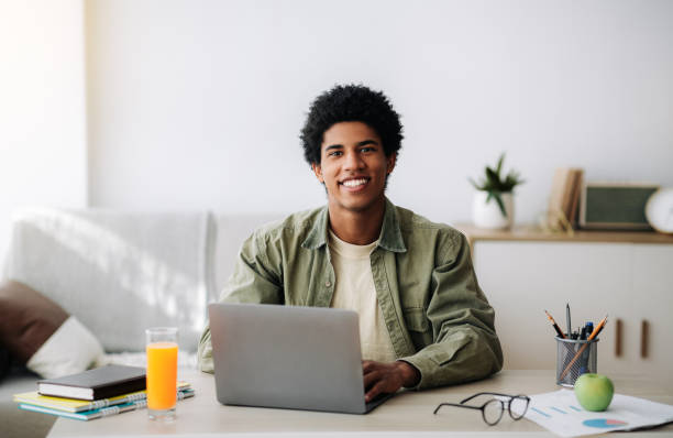 istock Web based schooling concept. Happy black teenager using laptop for online education at home 1288095694