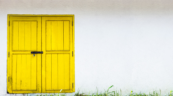 Yellow door on white wall, copy space