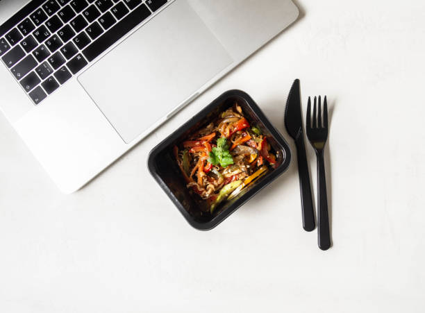 istock Black plastic container with vegetables stir fry and laptop 1288098056