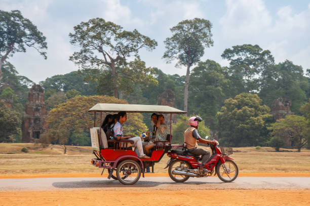 Rickshaw tuk-tuk Siem Reap, Cambodia - February, 2013: Rickshaw tuk-tuk with Asian tourists on the road to Angkor Thom temple, Cambodia siem reap stock pictures, royalty-free photos & images